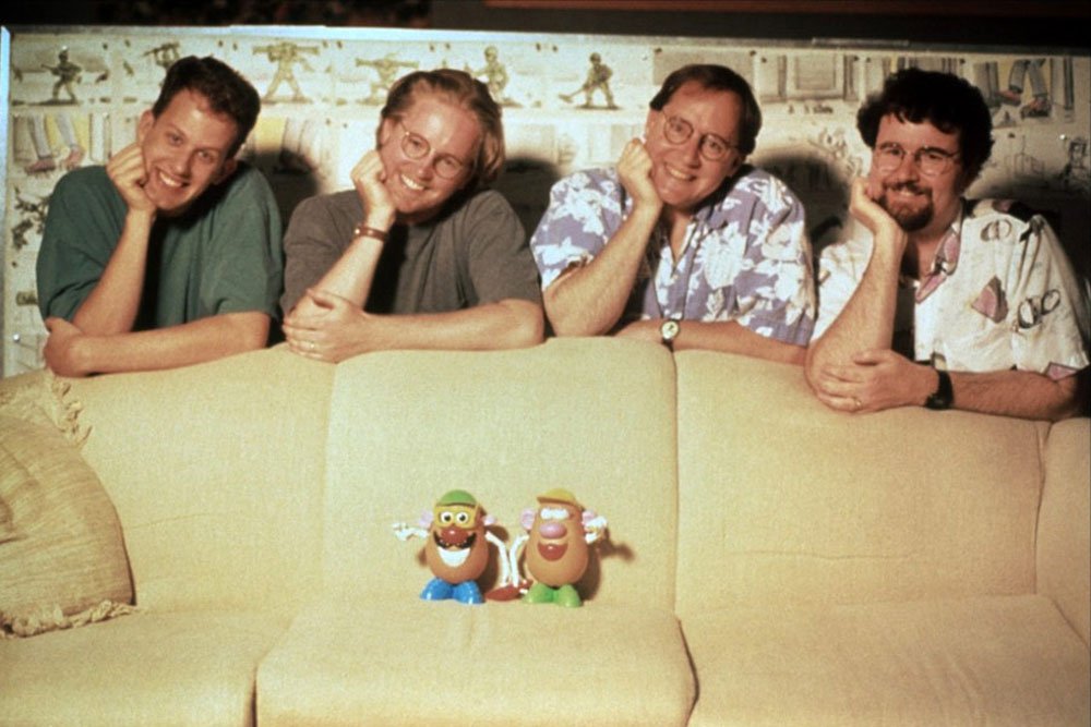The four filmmakers leaning over a couch with Mr. and Mrs. Potato Head toys